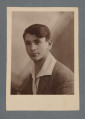 Fotografia monochromatyczna, w sepii, przedstawia uśmiechniętego młodego mężczyznę, tego samego i zapewne w tej samej marynarce i koszuli co na zdjęciu wcześniejszym, w klapie marynarki nie ma jednak, w odróżnieniu od tamtego, przypinki.Kołnierzyk - duży - białej koszuli wyłożony na ciemną (nie czarną) marynarkę.Pieczątka zakładu fotograficznego pozwala domniemywać, że zdjęcie nie zostało wykonane przed 1930 - w kolekcji znajdują się zdjęcia z dedykacjami z różnych okresów, wywołanych w tym zakładzie - niektóre zdjęcia z dedykacjami z 1930 r. i wcześniejszymi mają jeszcze inną pieczątkę firmową.Krawędzie proste, wzdłuż których jasny margines, większy u dołu.W lewym górnym rogu rewersu widoczny nr czarnym piórem: 13[?]810 - skośnie. rewers z zabrudzeniem.