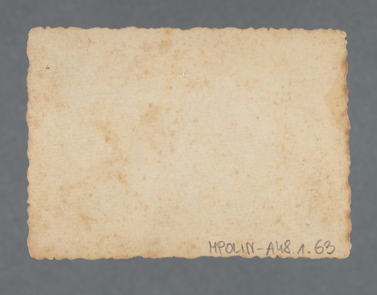 Fotografia trzech kobiet na skarpie. Jedna z nich - ubrana w kraciastą sukienkę, ale być może i druga, ubrana w jasną sukienkę i w jasnym kapeluszu na głowie – widoczne również na zdjęciu poprzednim w kolekcji. Wchodzą, trzymając się za ręce, na piaszczystą górę. Nad nimi widoczne na szczycie dwoje dzieci i kobieta. Wzdłuż krawędzi prostokątny biały margines. Krawędzie ząbkowane.