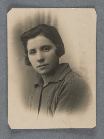 Fotografia portretowa kobiety (być może wychowawczyni Głównego Domu Opieki w Warszawie, widocznej na innych zdjęciach w kolekcji, por. kolejne w serii czy 1.16; to zdjęcie z wszystkich przedstawia ją, jak się wydaje, w najmłodszym wieku). Kobieta w ciemnych włosach za do wysokości uszu, ciemnym swetrze czy bluzce z kołnierzem. Uchwycona pod skosem. Postać wywołana na prostokątnej karcie z białym zaokrąglonym marginesem o rozmytych krawędziach. Krawędzie karty proste, rogi ścięte.