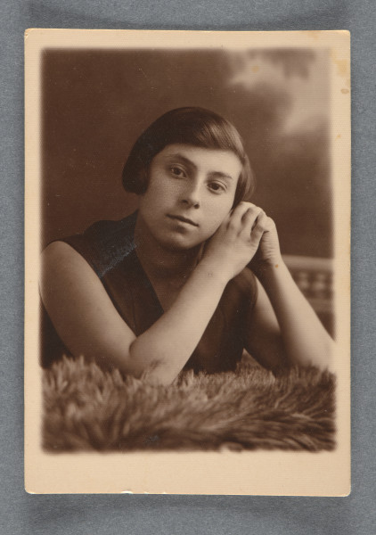 Fotografia Sary Tenenbaum na tle atelierowym (przedstawienie kamiennej klasycyzującej balustrady po prawej, u góry przedstawienie chmur), podpartej łokciami na leżącym przed nią futrze (?). Ramiona i ręce odkryte, ubrana w ciemną bluzkę. Włosy półkrótkie, zaczesane na bok (podobnie jak na zdjęciu 4 w serii).Krawędzie proste, z marginesem białym.