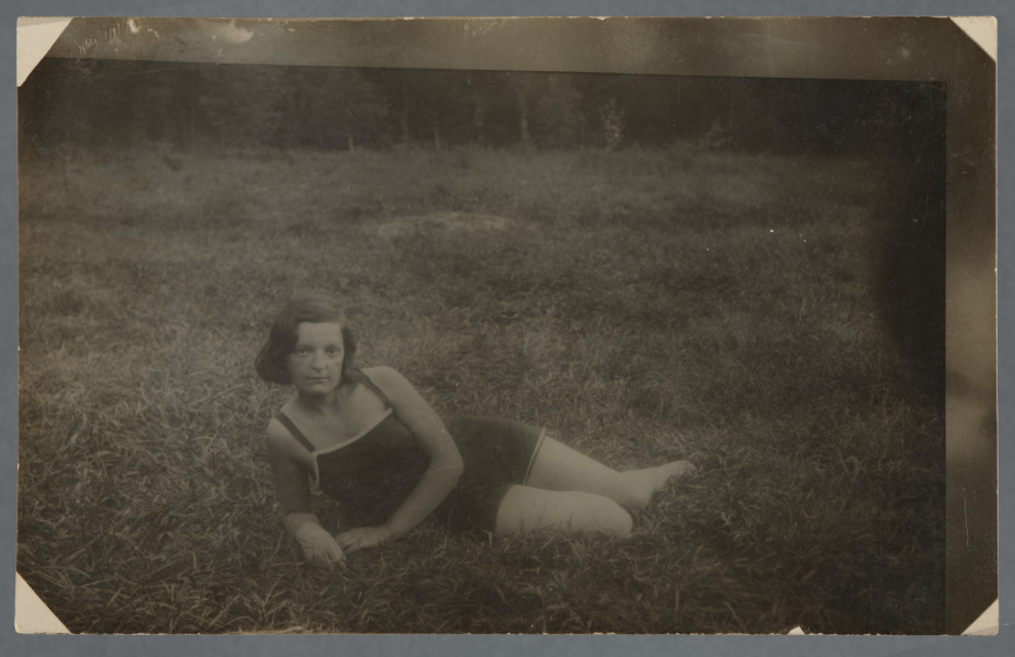 Fotografia Feli Cytrynówny w plenerze, jak wynika z opisu ręką Mani Żelaznej (?) na odwrocie: młoda kobieta leży bokiem w ciemnym stroju kąpielowym na trawie lub wśród ziół, patrzy w obiektyw. Nie uśmiecha się.Fotografia wywołana z białymi narożnikami, prawa i górna krawędzie z pasmem nienależącym do obrazu zdjęcia - fotografia być może przefotografowana. Krawędzie odbitki proste.Por. zdjęcie grupowe w kolekcji - 1.13, na nim również jest, wg opisu, przedstawiona Fela Cytrynówna.