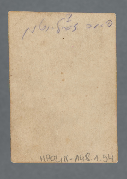 Fotografia portretowa kobiety z medalionem na szyi, en face, na tle ciemnej pofałdowanej kotary. Ubrana w bluzkę z krótkimi rękawami, włosy za uszy, z grzywką.Krawędzie karty proste, widoczny cienki margines.