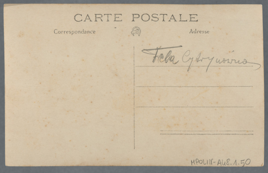 Fotografia Feli Cytrynówny w plenerze, jak wynika z opisu ręką Mani Żelaznej (?) na odwrocie: młoda kobieta leży bokiem w ciemnym stroju kąpielowym na trawie lub wśród ziół, patrzy w obiektyw. Nie uśmiecha się.Fotografia wywołana z białymi narożnikami, prawa i górna krawędzie z pasmem nienależącym do obrazu zdjęcia - fotografia być może przefotografowana. Krawędzie odbitki proste.Por. zdjęcie grupowe w kolekcji - 1.13, na nim również jest, wg opisu, przedstawiona Fela Cytrynówna.