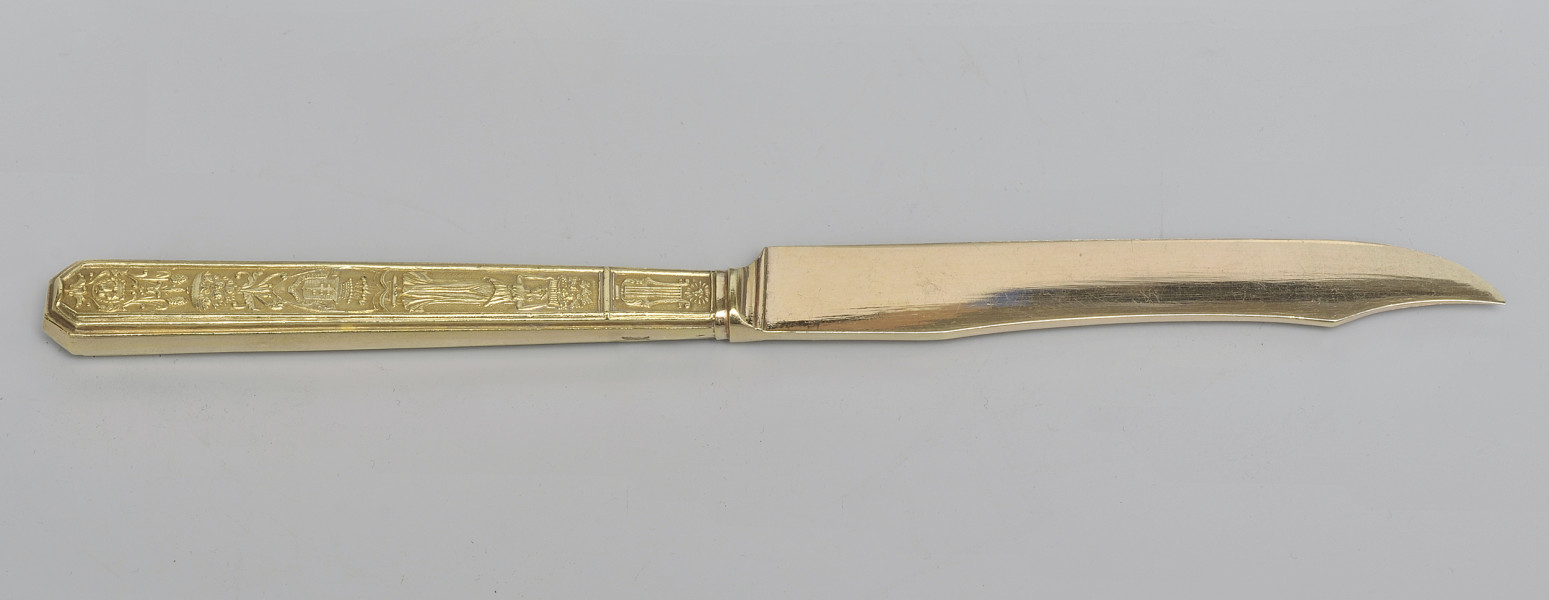 ujęcie 3/4 - strona z gładką głownią. Ujęcie z widocznym grzbietem. Czubek ostrza skierowany w prawą stronę.