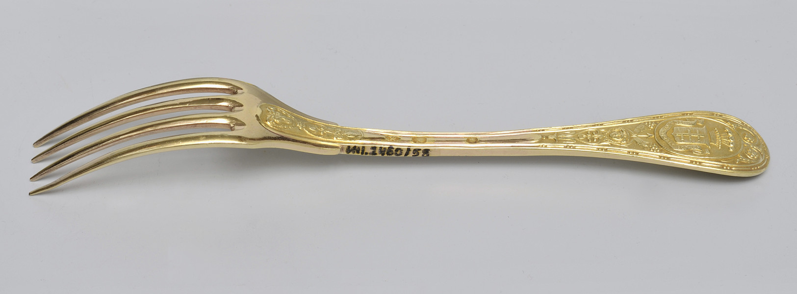 ujęcie 3/4 – od strony rewersu. Zębiska po lewej stronie; w górnej części bocznej krawędzi rączki napis inwentarzowy.