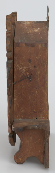 Pięciokątna szafka osadzona na prostokątnej podstawie. W dolnej części podstawy drążek. Drzwiczki do szafki z owalnym lustrem w rzeźbionej ramie o nieregularnym konturze, osadzone na dwóch zawiasach, zamykane na podłużny haczyk. W środku miejsce na schowanie drobnych rzeczy. Z dwóch stron lustra umieszczone są stojące lwy, z głowami odwróconymi na zewnątrz. Nad i pod lustrem rzeźbione motywy floralne i liście. Lwie grzywy oraz tło są w ciemniejszym odcieniu drewna. Na szczycie szafki, z tyłu, umieszczona została blaszana zawieszka. 