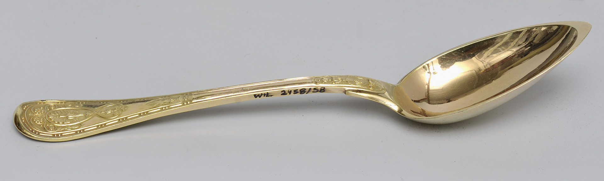 ujęcie 3/4 - widoczna wewnętrzna strona czerpaka. Ujęcie z nabierakiem po prawej stronie i napisem inwentarzowym na bocznej krawędzi rączki.