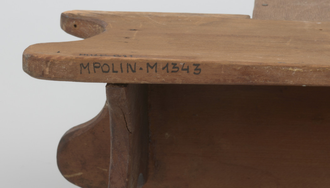 Pięciokątna szafka osadzona na prostokątnej podstawie. W dolnej części podstawy drążek. Drzwiczki do szafki z owalnym lustrem w rzeźbionej ramie o nieregularnym konturze, osadzone na dwóch zawiasach, zamykane na podłużny haczyk. W środku miejsce na schowanie drobnych rzeczy. Z dwóch stron lustra umieszczone są stojące lwy, z głowami odwróconymi na zewnątrz. Nad i pod lustrem rzeźbione motywy floralne i liście. Lwie grzywy oraz tło są w ciemniejszym odcieniu drewna. Na szczycie szafki, z tyłu, umieszczona została blaszana zawieszka. 