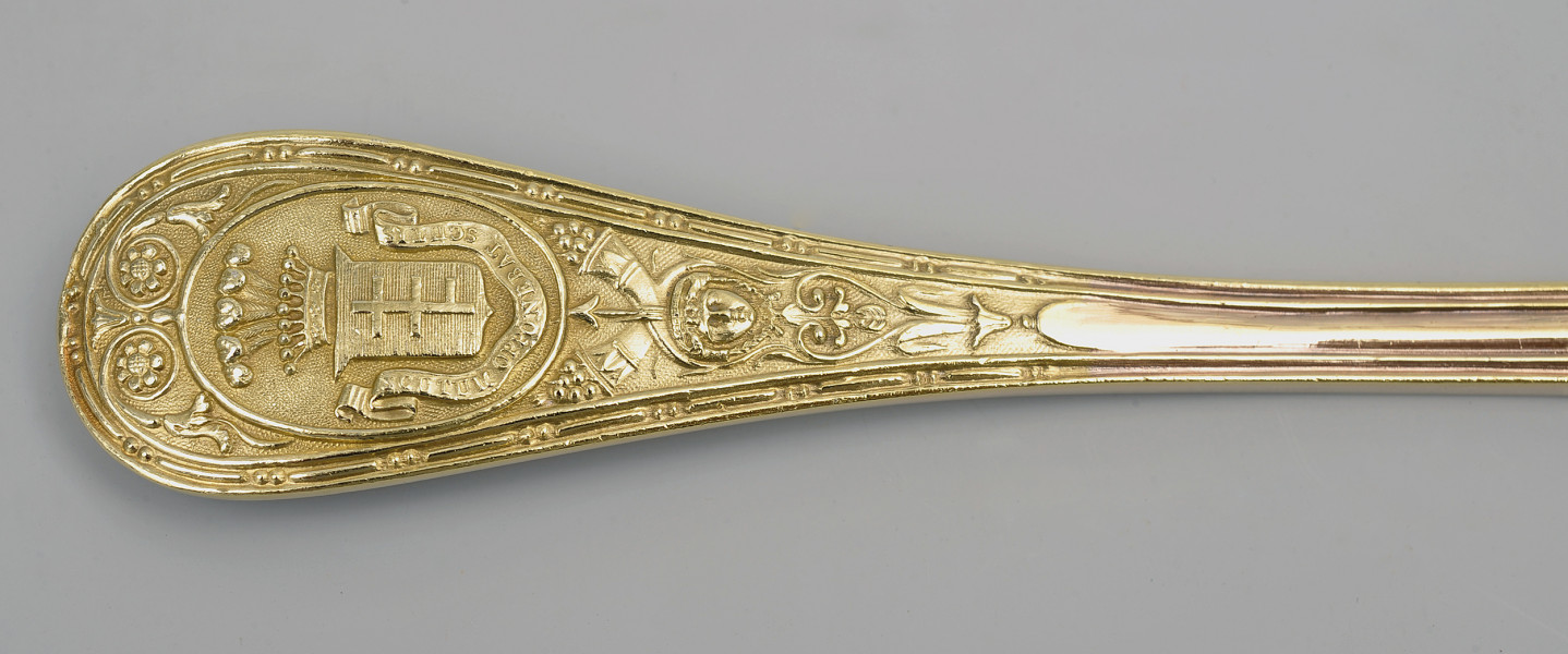 zbliżenie na półkoliście zakończony trzonek z herbem Potockich Pilawa – rewers. Herb pod koroną hrabiowską ze strusimi piórami i napisem obiegającym tarczę od dołu. 