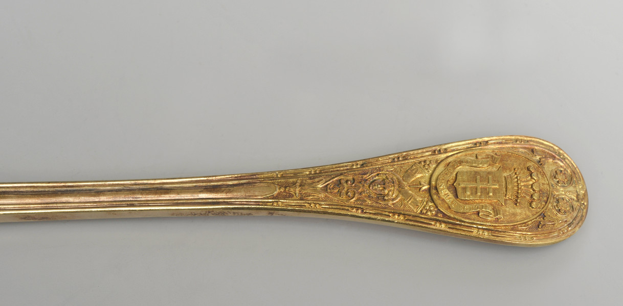 zbliżenie na uchwyt z herbem Potockich Pilawa – rewers. Zdobione zakończenie rączki po prawej stronie.