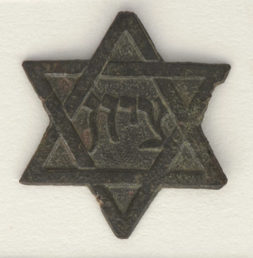Emblemat wykonany z metalu w kształcie gwiazdy sześcioramiennej (gwiazda Dawida). W centralnym miejscu gwiazdy umieszczono napis w języku hebrajskim: ציון (pol. Syjon).