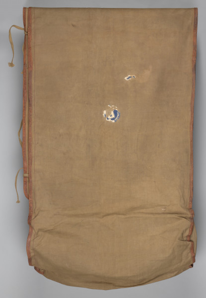 Śpiwór uszyty z płótna bawełnianego o grubym splocie w kolorze jasnobrązowym. Śpiwór posiada kształt kopertowy. Konstrukcja śpiwora składa się ze środkowej płaszczyzny w formie długiej kieszeni zakrywającej ciało. Kieszeń zamykana jest na dwie klapy: lewa, mniejsza, oraz prawa, szersza. Śpiwór posiada dwie kieszenie: dolną w formie prostokąta, górną, która może stanowić rodzaj ochraniacza, w który można zrolować całość. Wykończenie śpiwora wykonane jest ze skórzanej lamówki, znajduję się ona na całej długości, a także na wewnętrznych krawędziach śpiwora. Duża klapa posiada na brzegu rozłożone symetryczne trzy metalowe nity. W przeciwległym rogu śpiwora przyszyte są bawełniane sznurki. Na brzegach pokrowca znajdują się również dwa nity i dwa troki przyszyte do brzegów podszewki.
W dolnej partii śpiwora; na zewnętrznej stronie, znajdują się dwie skórzane szlufki.
Dodatkowo w środkowej partii znajduję się papierowa, okrągła nalepka (destrukt). Na nalepce widoczna litera B w kolorze granatowym.