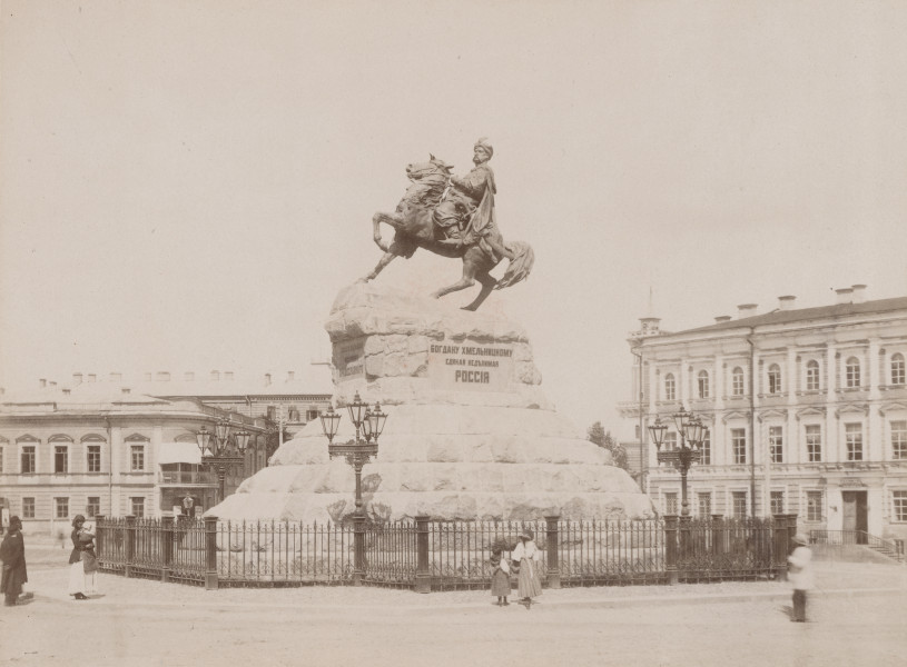 zbliżenie na zdjęcie przedstawiające pomnik hetmana na koniu. Monument na wysokim cokole, na którym niezachowana do dziś tablica inskrypcyjna głoszącą: „Bogdanowi Chmielnickiemu jedna niepodzielna Rosja”. Całość otoczona ażurowym, metalowym parkanem