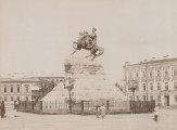 zbliżenie na zdjęcie przedstawiające pomnik hetmana na koniu. Monument na wysokim cokole, na którym niezachowana do dziś tablica inskrypcyjna głoszącą: „Bogdanowi Chmielnickiemu jedna niepodzielna Rosja”. Całość otoczona ażurowym, metalowym parkanem