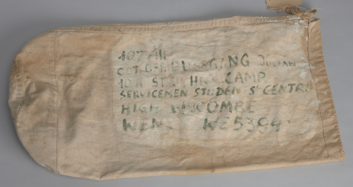 Pokrowiec jest w kolorze jasnobrązowym z napisami koloru zielonego w języku angielskim:  107/III ; CD[?]T.G[?]FF. BUSSGANG ; 10A ST. JOHN CAMP ; SERVICEMEN STUDENTS' CENTRE ; HIGH WYCOMBE ; WENX[?] W6[?]5394. W górnej części, po lewej stronie znajdują się skórzane rzemyki służące do wiązania całości pokrowca. W wewnętrznej części pokrowca widoczny fragment naszywki (prawdopodobnie metki) w kolorze jasnobrązowym.