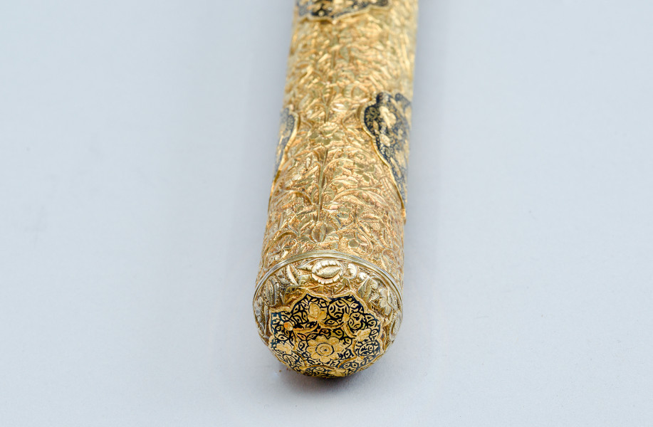 zbliżenie na zakończenie trzonka z dekoracją rozety - ujęcie z dołu. Rękojeść obita srebrną, pozłacaną blachą, zdobioną niellowanymi ornamentami.