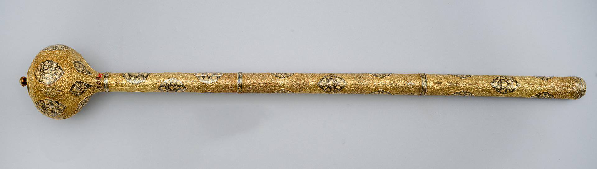 strona pierwsza. Pod kulistą głowicą, nad pierwszym pierścieniem rękojeści naniesiony numer inwentarzowy.