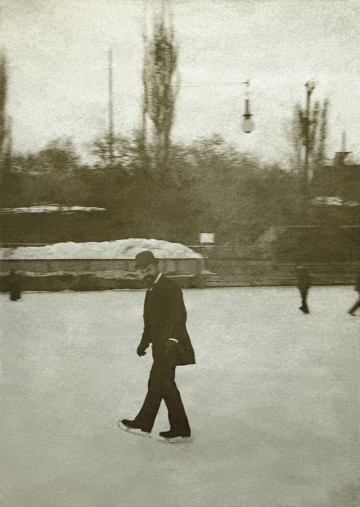 Na zdjeciu znajduje się mężczyzna w meloniku jadący na łyżwach.