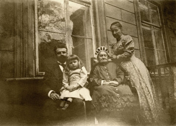 Na zdjęciu znajduje się cztery osoby przed ścianą pałacu.