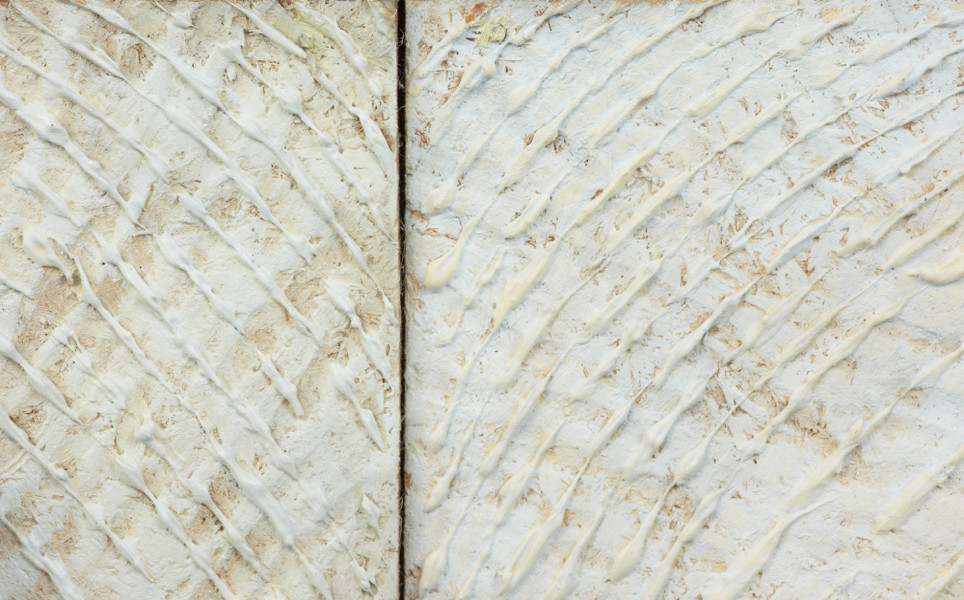 dyptyk - Widok detalu. Dwa kwadratowe obrazy połączone ze sobą tworząc poziomą kompozycję. Płaszczyzna obu utrzymana w jasnej monochromatycznej tonacji z uformowanymi wzniesieniami i wgłębieniami. Nad obiema częściami zawieszone od góry na żyłkach kwadratowe, transparentne płytki pleksi z wtopionymi weń nieregularnymi, płaskimi, kolorowymi elementami po bokach. W centrum płytki, w lewej części pracy, naklejone polakierowane na czarno dwie wklęsłe formy: jedna większa, elipsoidalna, druga podłużna, wygięta okala lewą stronę większej bryły. W prawej części, centralnie na płytce umieszczone blisko siebie dwie białe wypukłe formy. Większą bryłę, z prawej strony okala mniejsza. Cała kompozycja, w swych głównych elementach zbudowana jest na przeciwieństwach: wklęsłe-wybrzuszone, białe-czarne, pozytyw-negatyw.