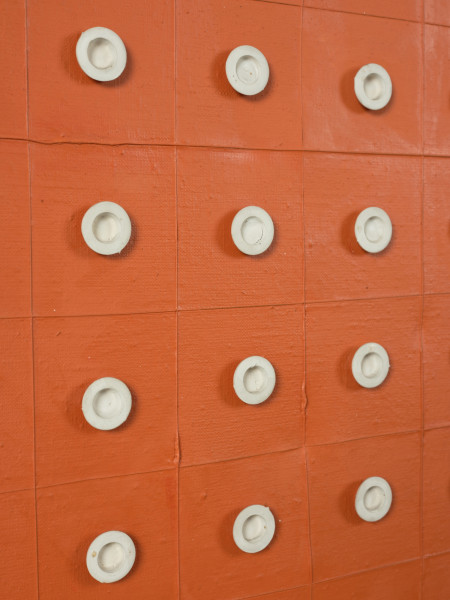 malarstwo; obraz; Układ 2 - Ujęcie detalu z centrum obrazu skosem w lewą stronę. Kompozycja pionowa. Rdzawopomarańczowa płaszczyzna, z siatką kwadratowych pól (12 poziomo, 15 pionowo) wyznaczoną przez cienką wypukłą linię. W środku każdego kwadratu, oprócz rzędów zewnętrznych przy krawędziach obrazu, umieszczono biały, okrągły element z tworzywa sztucznego. W części centralnej obrazu 32 kwadraty z krążkami większymi i dodatkowo wklęsłymi tworzą prostokątny obszar. Pozostałe krążki mają płaską powierzchnię. Przy dolnej krawędzi z lewej strony, pod czwartym kwadratem, dwa białe punkty obok siebie zaburzają asymetrycznym układem regularną strukturę całości.