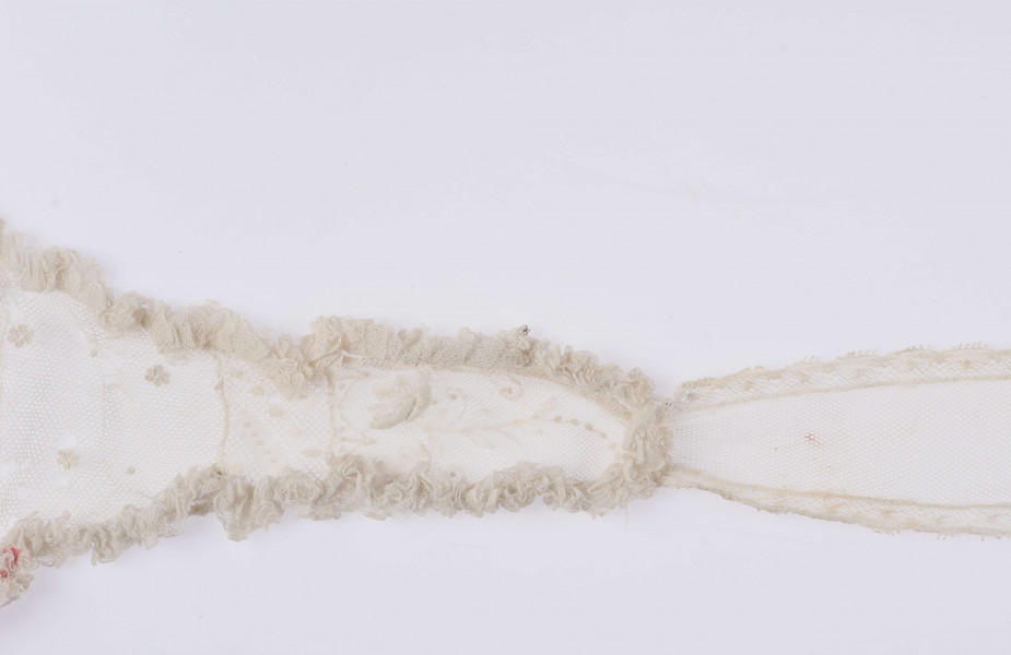 E/123/MRK/ML - Czepek tiulowy z 2 wstążkami, biały tiul po środku różowy pasek. Brzegi czepka pofałdowane. Dł. wstążek 70 cm, szer. 12 cm. Wstążki haftowane wzorem kwiatowym. Czepek dł. 49 cm i szer. 11 cm. Brzegi obszyte wąską falbanką  po środku wstawka z koronki i tiulu szer. 6 cm. 