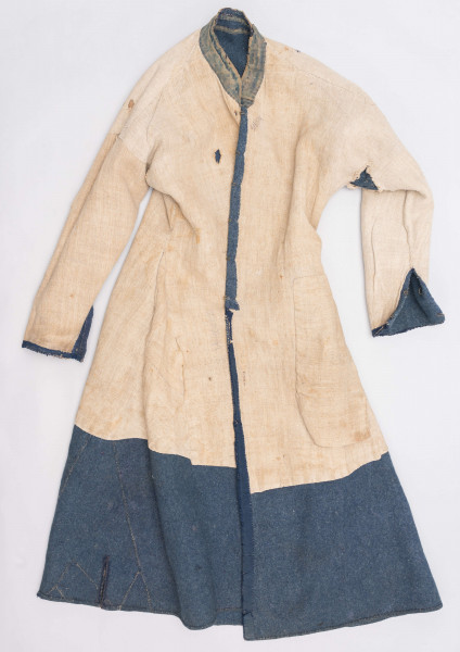 E/308/MRK/ML - Sukmana męska szaro-granatowa z metalowymi guzikami. Kołnierz - stójka dł. 43 cm, szer. 5 cm, rękaw wszywany prosty dł. 56 cm, szer. 15 cm. Krój prosty, w pasie po obu stronach zaszewki /13/, lniana podszewka, sukmana zapina na 6 haftek, ozdobiona taśmą szer. 1 cm i metalowymi guzami /7/. Dł. 123 cm, szer. 49 cm.