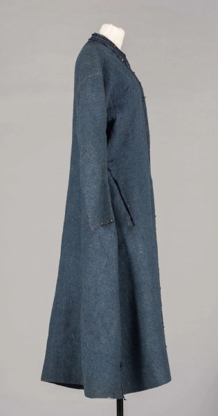 E/191/MRK/ML - Sukmana męska  krój prosty, w kolorze szaro-granatowym, dł. 135 cm, szer. 47 cm, z kołnierzem-stójką dł. 43 cm, szer. 5 cm. Rękaw wszywany prosty dł. 56 cm, szer. 15 cm. Sukmana zapinana na 6 metalowych haftek, ozdobiona granatową taśmą szer. 1 cm, małymi metalowymi guzikami (część brak), obszyta granatową wełną. W psie sukmany, po obu kokach po 3 zaszewki, z jednego boku niezszyta kieszeń szer. 20 cm. Pod spodem lniana podszewka. U dołu, po bokach, rozcięcia dł. 11 cm. W materiale widocznych kilka dziur.