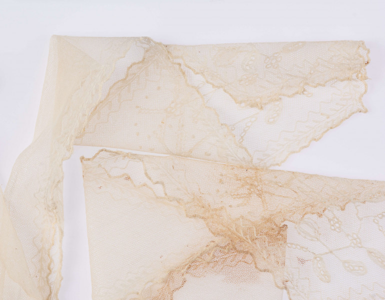 E/124/MRK/ML - Czepek tiulowy, biały tiul, wzory o motywach roślinnych, brzegi pofałdowane. Dług. wstążek 45 cm, szer. 8 cm, brzegi obszyte białą koronką szer. 1 cm. Czepek dł. 50 cm szer. 18 cm. W części środkowej wstawka szer. 10 cm.