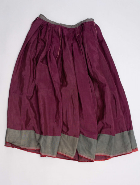 E/190/MRK/ML - Spódnica ze szczoteczką koloru biskupiego. Szyta ręcznie czarnymi nićmi. Spód obszyty szczoteczką. Obwód w pasie 67 cm. Obwód u dołu 322 cm. 