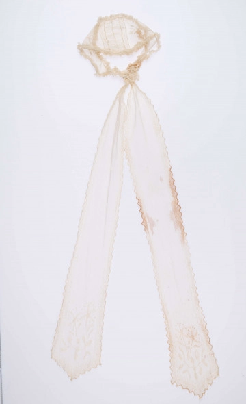 E/124/MRK/ML E/124/MRK/ML - Czepek tiulowy, biały tiul, wzory o motywach roślinnych, brzegi pofałdowane. Dług. wstążek 45 cm, szer. 8 cm, brzegi obszyte białą koronką szer. 1 cm. Czepek dł. 50 cm szer. 18 cm. W części środkowej wstawka szer. 10 cm.