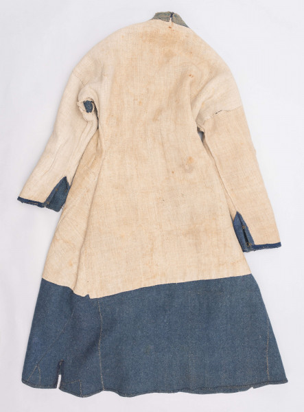 E/308/MRK/ML - Sukmana męska szaro-granatowa z metalowymi guzikami. Kołnierz - stójka dł. 43 cm, szer. 5 cm, rękaw wszywany prosty dł. 56 cm, szer. 15 cm. Krój prosty, w pasie po obu stronach zaszewki /13/, lniana podszewka, sukmana zapina na 6 haftek, ozdobiona taśmą szer. 1 cm i metalowymi guzami /7/. Dł. 123 cm, szer. 49 cm.