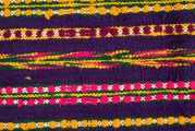 E/125/MRK/ML - Zapaska wełniana w różnokolorowe pasy, ułożone poziomo. Dł. zapaski 77 cm, szer. 98 cm, zszyta w środku. Kolory: fioletowy, niebieski, czerwony, biały, zielony, żółty, brązowy. Od góry 14 zakładek na nich naszyty lniany pasek szer. 1 cm, dł. 65 cm.