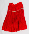 E/516/MRK/ML - Spódnica krakowska. Wykonana z wełenki, kolor czerwony. W dolnej czesci spódnica ozdobiona różnokolorowymi tasiemkami, sztuk 7. Przy oszewce lekko marszczona.