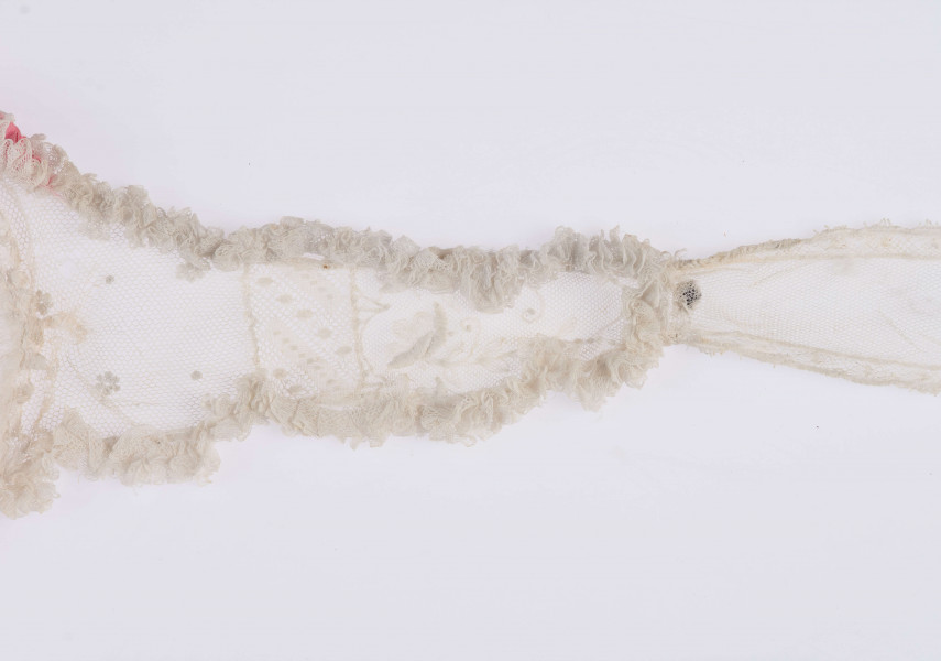 E/123/MRK/ML - Czepek tiulowy z 2 wstążkami, biały tiul po środku różowy pasek. Brzegi czepka pofałdowane. Dł. wstążek 70 cm, szer. 12 cm. Wstążki haftowane wzorem kwiatowym. Czepek dł. 49 cm i szer. 11 cm. Brzegi obszyte wąską falbanką  po środku wstawka z koronki i tiulu szer. 6 cm. 