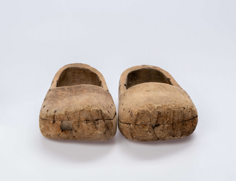 E/13/MRK/ML - Drewniaki dłubane, para. Długość 31 cm. Zrobione z dwóch kawałków drewna zbitych gwoździami. Z boku otwory do wiązania.