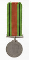 H/2050/MRK/ML - Odznaką jest medal bity w miedzioniklu 3,6 cm średnicy, o gładkim rancie. Na awersie jest lewy profil głowy króla Jerzego VI, przy zarycie szyi sygnatura HP. W otoku napis: GREGORIUS VI D:G:BR:OMN:REX F:D:IND:IMP. Na rewersie dąb zwięczony koroną zamkniętą, oraz dwa ryczące, wspięte na tylnych łapach lwy, za ich grzbietami daty 1939 i 1945. Dąb wyrasta z lądu oblanego wodą (wyspa). Poniżej w dwóch wierszach napis: THE DEFENCE MEDAL. Przywieszka w formie szlufy na wstążkę nitowana z medalem. Wstążka szerokości 3,2 cm, od brzegów jasnozielone pasy z czarnym prążkiem, w środku pas pomarańczowo-ceglasty.