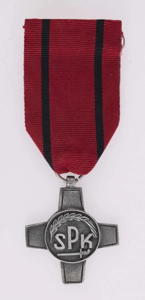 H/2463/MRK/ML - Odznaką jest krzyż bity w białym metaluo obramowanych ramionach, w środku okrągła tarcza z napisem SPK poniżej miecz, u góry otokowo kłos, wstążka czerwona z 2 czarnymi paskami.

