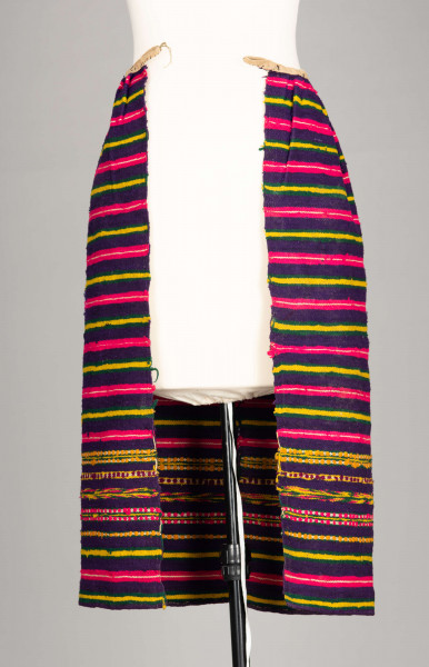 E/125/MRK/ML - Zapaska wełniana w różnokolorowe pasy, ułożone poziomo. Dł. zapaski 77 cm, szer. 98 cm, zszyta w środku. Kolory: fioletowy, niebieski, czerwony, biały, zielony, żółty, brązowy. Od góry 14 zakładek na nich naszyty lniany pasek szer. 1 cm, dł. 65 cm.