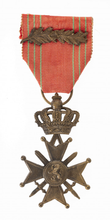 Odznaką Croix de Guerre jest krzyż równoramienny o wym. 3,8 x 3,8 cm. Ramiona krzyża matowe z obramowaniem, rozszerzają się od 0,5 do 1,7 cm, zakończone kulkami, z trójkątnym wcięciem. Pomiędzy ramionami skrzyżowane dwa miecze długości 3,5 cm. Medalion krzyża mocno uwypuklony z herbem Belgii (lew wspięty na tylych nogach). Przy górnym ramieniu przywieszka zawiasowo połączona z zamkniętą koroną ośmioramienną, zwieńczoną kulą z krzyżem. Korona w przekroju poziomym eliptyczna. W kulistym zwieńczeniu korony otwór z przełożonym kółkiem. Wstążka odznaczenia szerokości 3,8 cm czerwona z sześcioma zielonymi paskami i nałożoną  poziomo gałązką palmową.