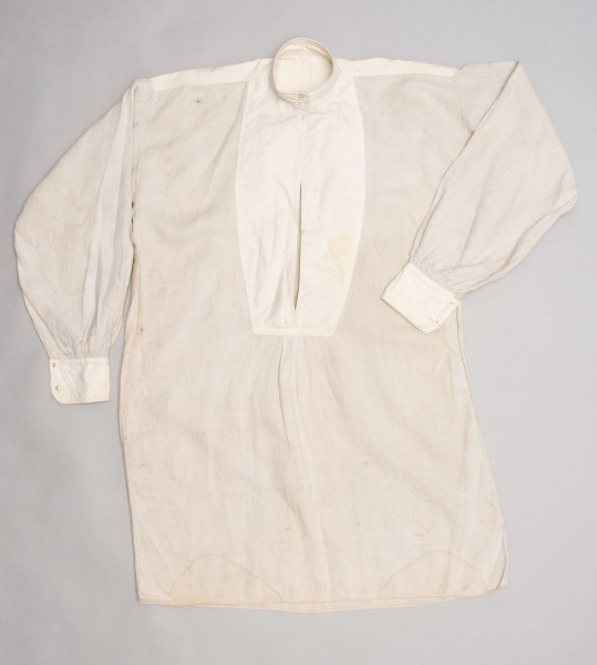 E/128/MRK/ML - Koszula lniana męska, biała, prosty i krótki kołnierzyk zapinany na 2 guziki, rękawy długie zapinane na 2 guziki. Dł. 101 cm, szer. 54 cm. Dł. rękawa 57 cm, szer. 20 cm, dł. mankietu 5 cm, szer. 11 cm. Z przodu koszuli rozcięcie  dł. 37 cm.  
