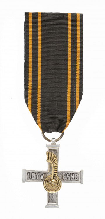 H/467/MRK/ML - Odznaką Krzyża 1 Dywizji Pancernej jest krzyż wykonany z białego metalu o wymiarach 4,1 x 4 cm i szerokości ramion 0,7 cm. Powierzchnia krzyża z obydwu stron jest chropowata, z gładkim obramowaniem szer. 0,1 cm. Na pioziomych ramionach wypukły napis: 1 DYW. PANC. Na pionowych ramionach nałożona złocona miniaturka odznaki rozpoznawczej 1 Dyw. Pancernej szyszak na tle okrągłej tarczy ze skrzydłem husarskim. Krzyż noszony jest na czarnej wstążce szerokości 3,8 cm, z 4 pomarańczowymi prążkami przy jej krawędziach.