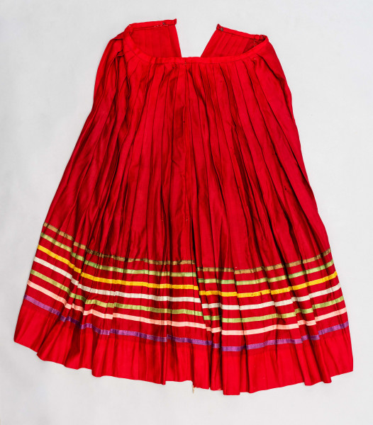 E/516/MRK/ML - Spódnica krakowska. Wykonana z wełenki, kolor czerwony. W dolnej czesci spódnica ozdobiona różnokolorowymi tasiemkami, sztuk 7. Przy oszewce lekko marszczona.