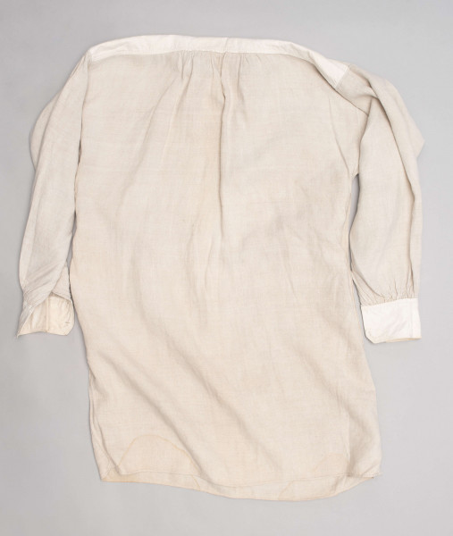 E/128/MRK/ML - Koszula lniana męska, biała, prosty i krótki kołnierzyk zapinany na 2 guziki, rękawy długie zapinane na 2 guziki. Dł. 101 cm, szer. 54 cm. Dł. rękawa 57 cm, szer. 20 cm, dł. mankietu 5 cm, szer. 11 cm. Z przodu koszuli rozcięcie  dł. 37 cm.  