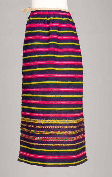 E/125/MRK/ML - Zapaska wełniana w różnokolorowe pasy, ułożone poziomo. Dł. zapaski 77 cm, szer. 98 cm, zszyta w środku. Kolory: fioletowy, niebieski, czerwony, biały, zielony, żółty, brązowy. Od góry 14 zakładek na nich naszyty lniany pasek szer. 1 cm, dł. 65 cm.