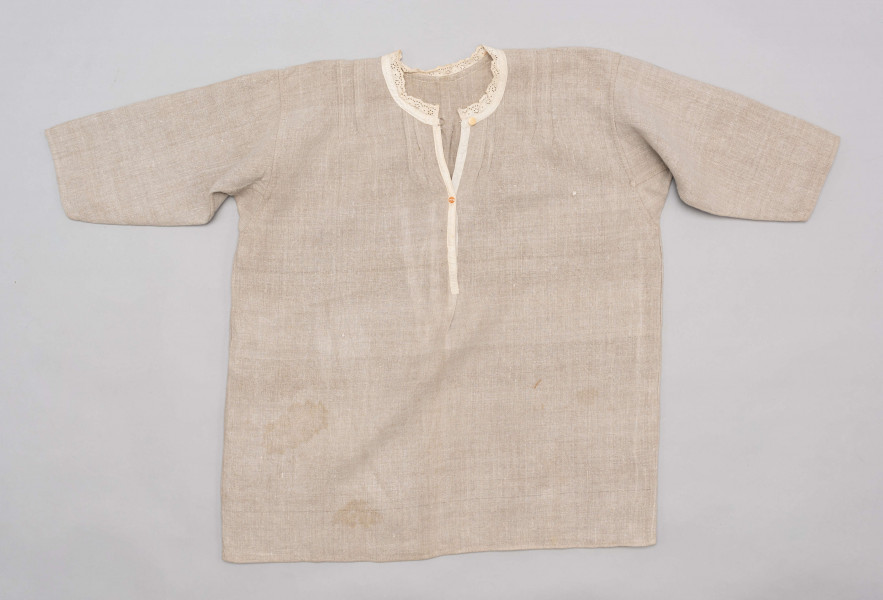 E/529/MRK/ML - Koszula damska. Uszyta z lnianego płótna z długimi rękawami, pod szyją dziurkowa pliska w kolorze białym. Na linii ramienia symetryczne zaszewki, pod szyjką pęknięcie zapinane na guzik.