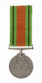 Odznaką jest medal bity w miedzioniklu średnicy 3,6cm, o gładkim rancie. Na awersie lewy profil głowy króla Jerzego VI. Przy zarysie szyi sygnatura HP. W otoku napis: Gregorius VI D:G:BR:OMN:REX F:D:IND:IMP. Na rewersie dąb wyrastający z lądu oblanego wodą, nad nim korona zamknięta. Po bokach dwa ryczące lwy, wspięte na tylnych łapach, przy rancie daty 1939  i 1945. U dułu w 2 wierszach napis: THE DEFENCE MEDAL. Przywieszka  w formie szlufy  na wstążkę nitowana do medalu. Wstążka szerokości 3,2 cm, od brzegów zielone pasy z czarnymi prążkimi wśrodku pas pomarańczowo-ceglasty