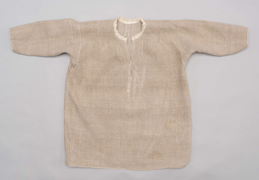 E/529/MRK/ML - Koszula damska. Uszyta z lnianego płótna z długimi rękawami, pod szyją dziurkowa pliska w kolorze białym. Na linii ramienia symetryczne zaszewki, pod szyjką pęknięcie zapinane na guzik.