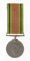 Odznaką jest medal bity w miedzioniklu średnicy 3,6cm, o gładkim rancie. Na awersie lewy profil głowy króla Jerzego VI. Przy zarysie szyi sygnatura HP. W otoku napis: Gregorius VI D:G:BR:OMN:REX F:D:IND:IMP. Na rewersie dąb wyrastający z lądu oblanego wodą, nad nim korona zamknięta. Po bokach dwa ryczące lwy, wspięte na tylnych łapach, przy rancie daty 1939  i 1945. U dułu w 2 wierszach napis: THE DEFENCE MEDAL. Przywieszka  w formie szlufy  na wstążkę nitowana do medalu. Wstążka szerokości 3,2 cm, od brzegów zielone pasy z czarnymi prążkimi wśrodku pas pomarańczowo-ceglasty