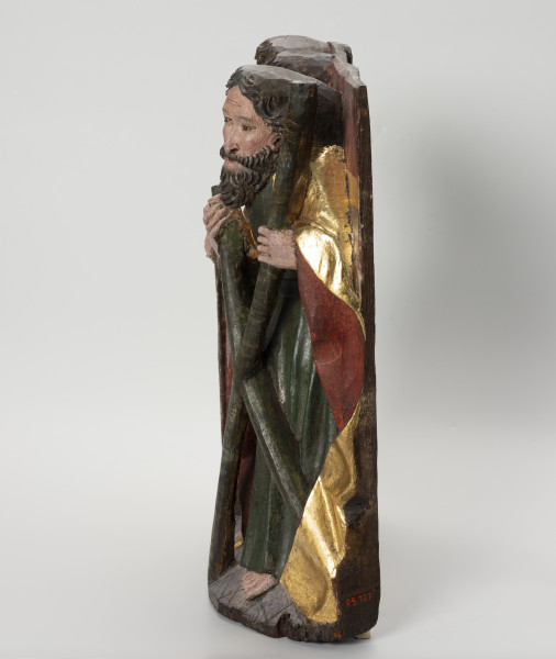 grupa rzeźbiarska - ujęcie z prawej; Płaskorzeźbiona płyta o kształcie stojącego prostokąta. Polichromowana i złocona. Widoczny jeden z apostołów stojących na szerokiej podstawie. Ubrani w tunikę i obszerną, plastycznie modelowaną szatę. Nosi długą kędzierzawą brodę. Przed sobą trzyma atrybut: św. Andrzej - krzyż o kształcie litery 